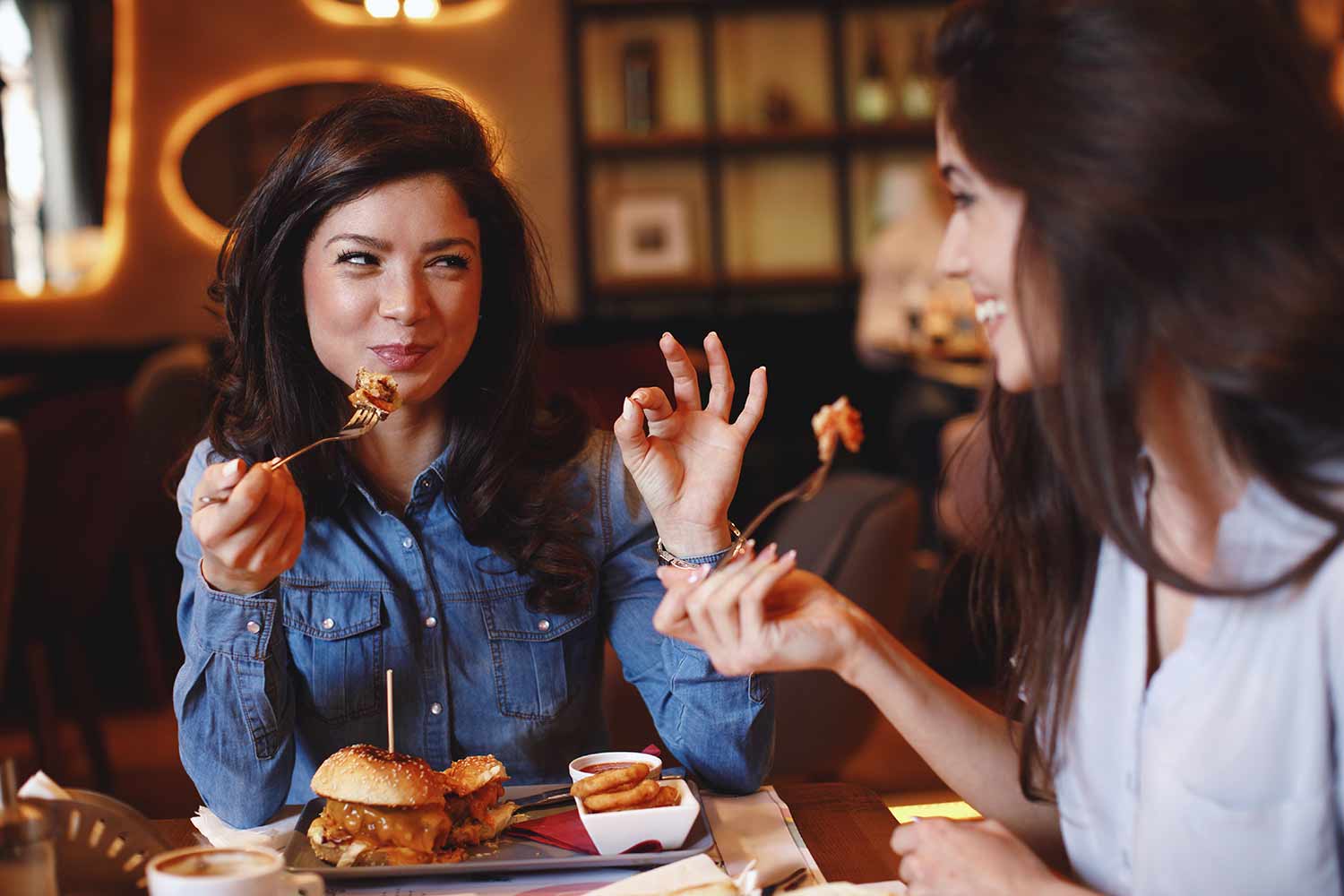 Two women at a burger restaurant laughing and enjoying food