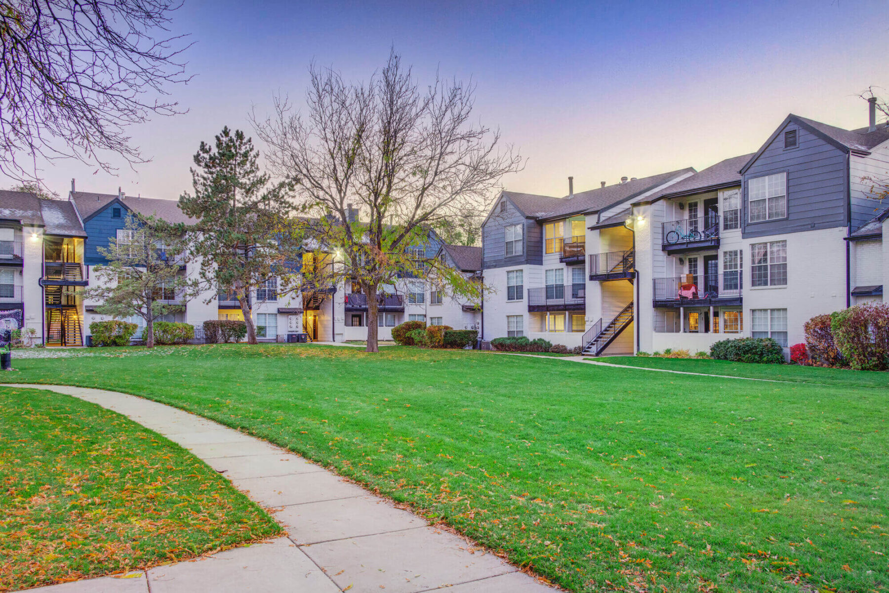 Green space in between residential buildings with tree lined sidewalks